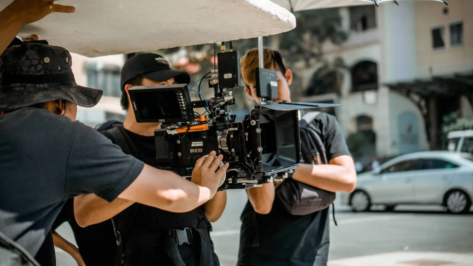 A camera crew working around a RED cinema camera on a city street